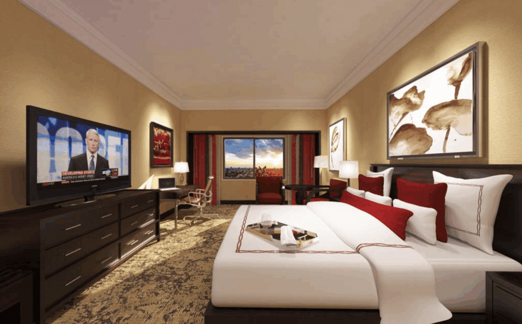 Cozy hotel suite with large bed, red pillows and warm lighting.